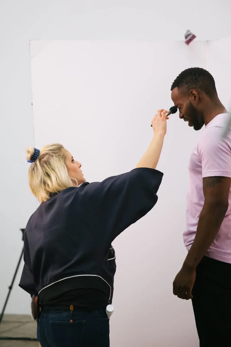 A makeup artist applying makeup to a man's face with a brush
