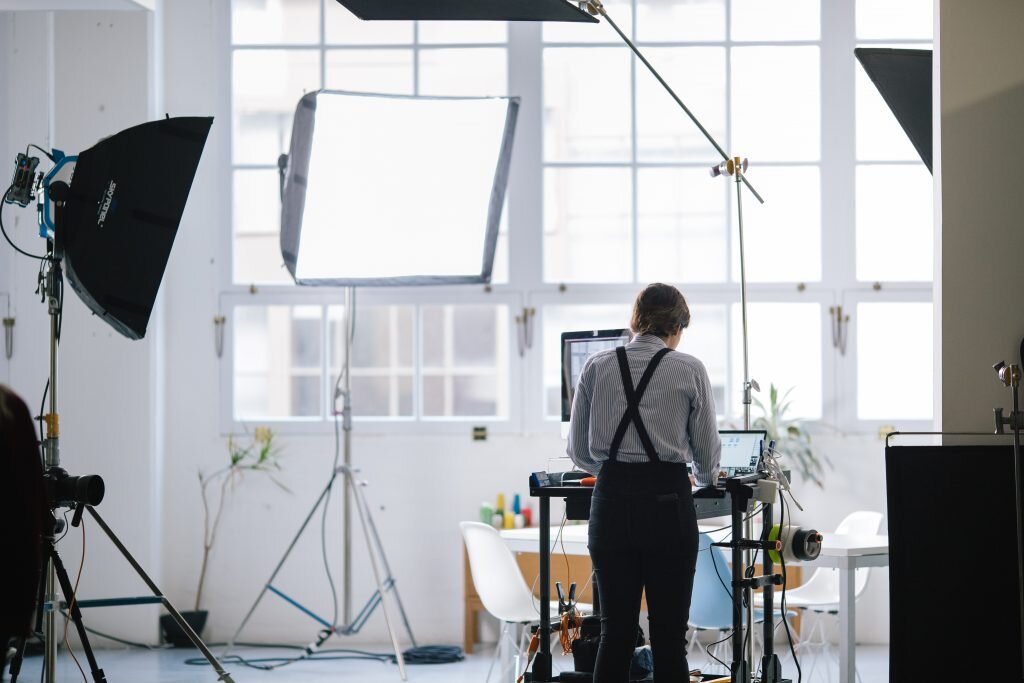 A person working in a photography or videography studio with professional lighting and equipment, and a computer.