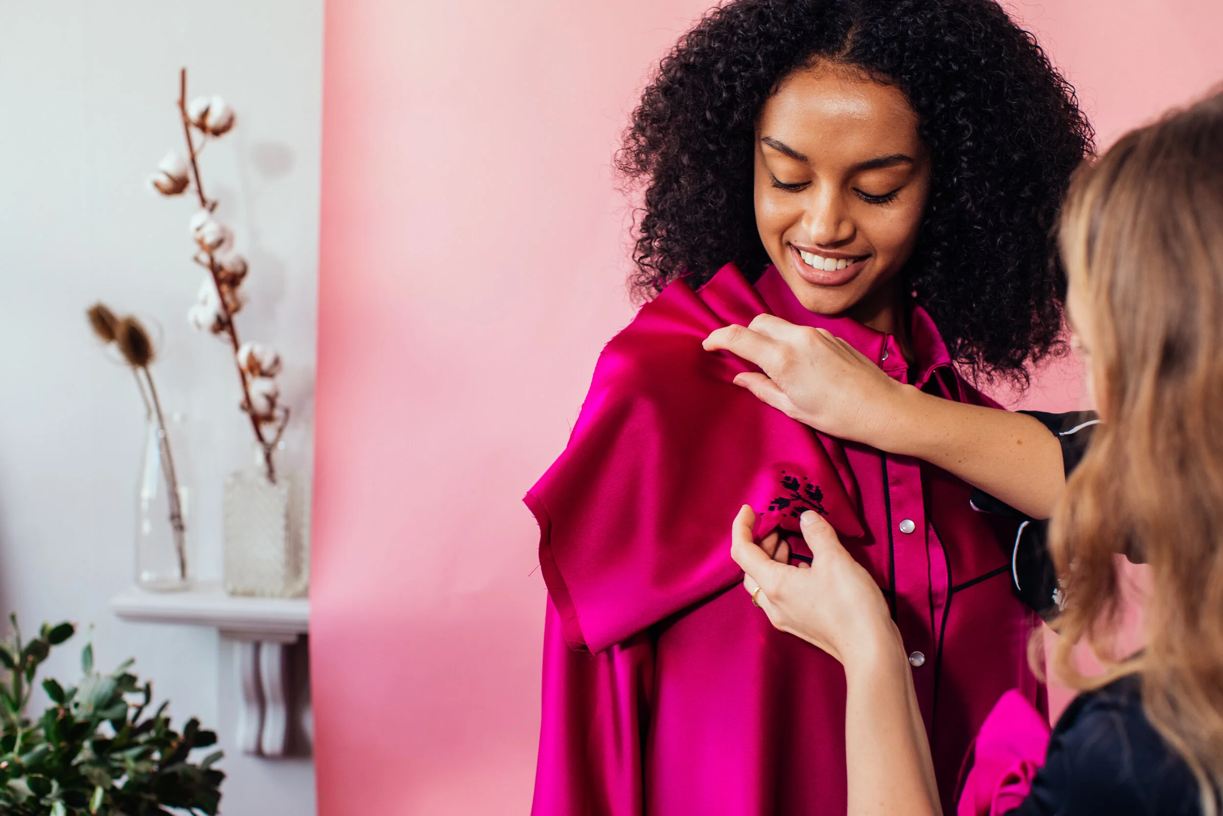 A woman wearing a pink satin jacket receiving a vaccination from a healthcare professional with another child present.
