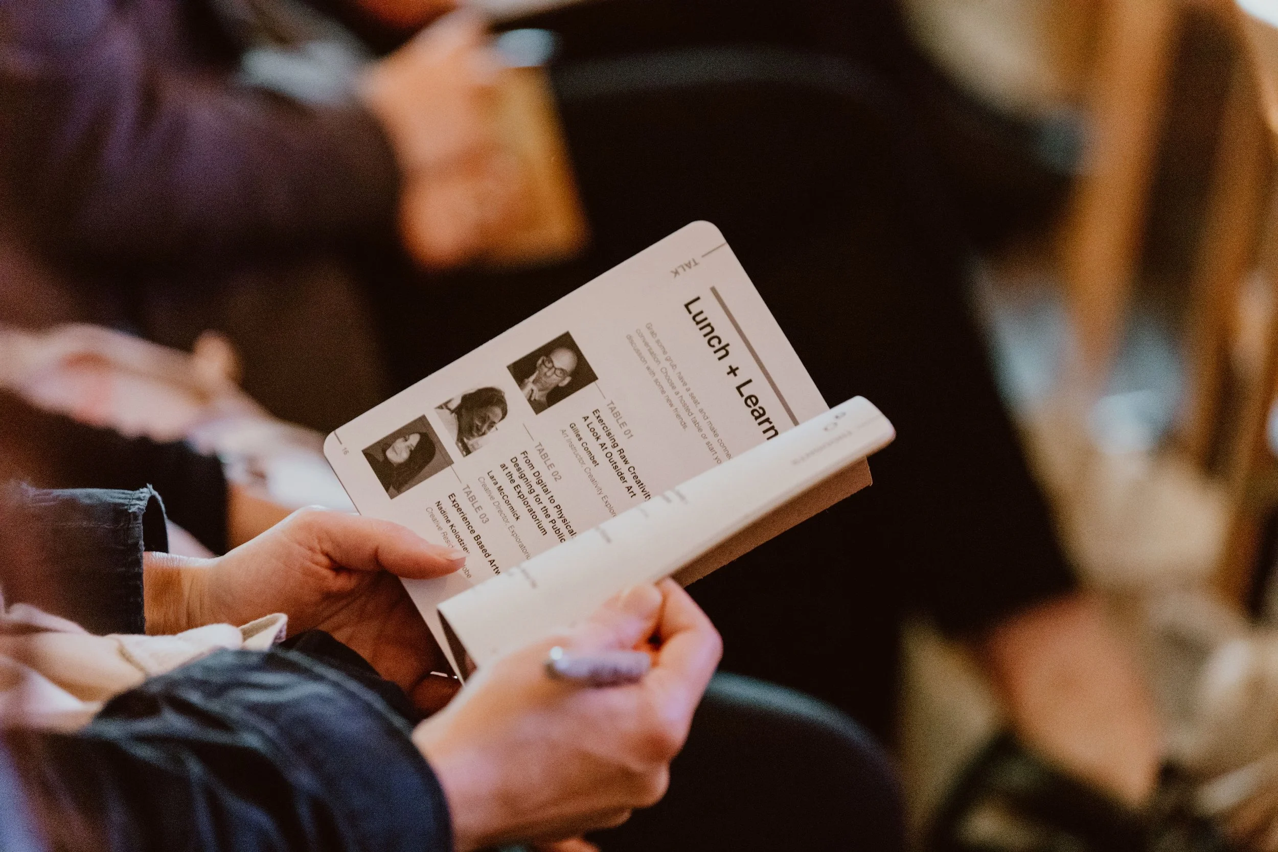 Person holding a printed conference schedule or program, focusing on the document.