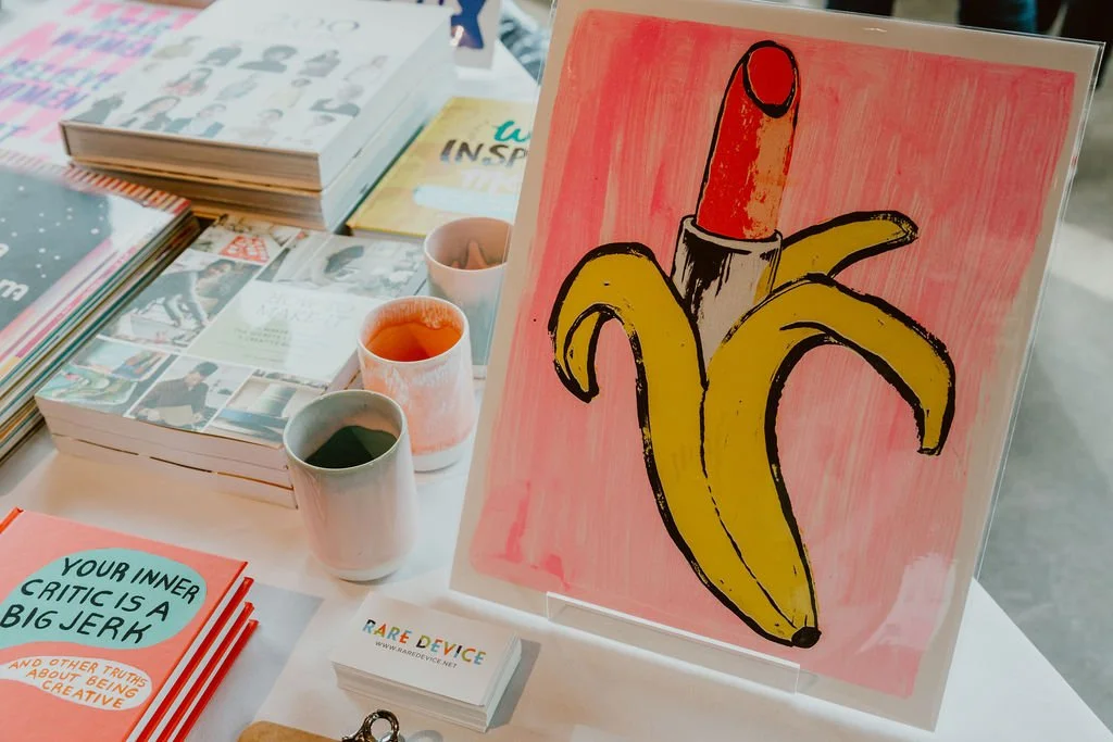 A painting of a peeled banana with a thumb created to resemble a human thumb, on a pink background.
