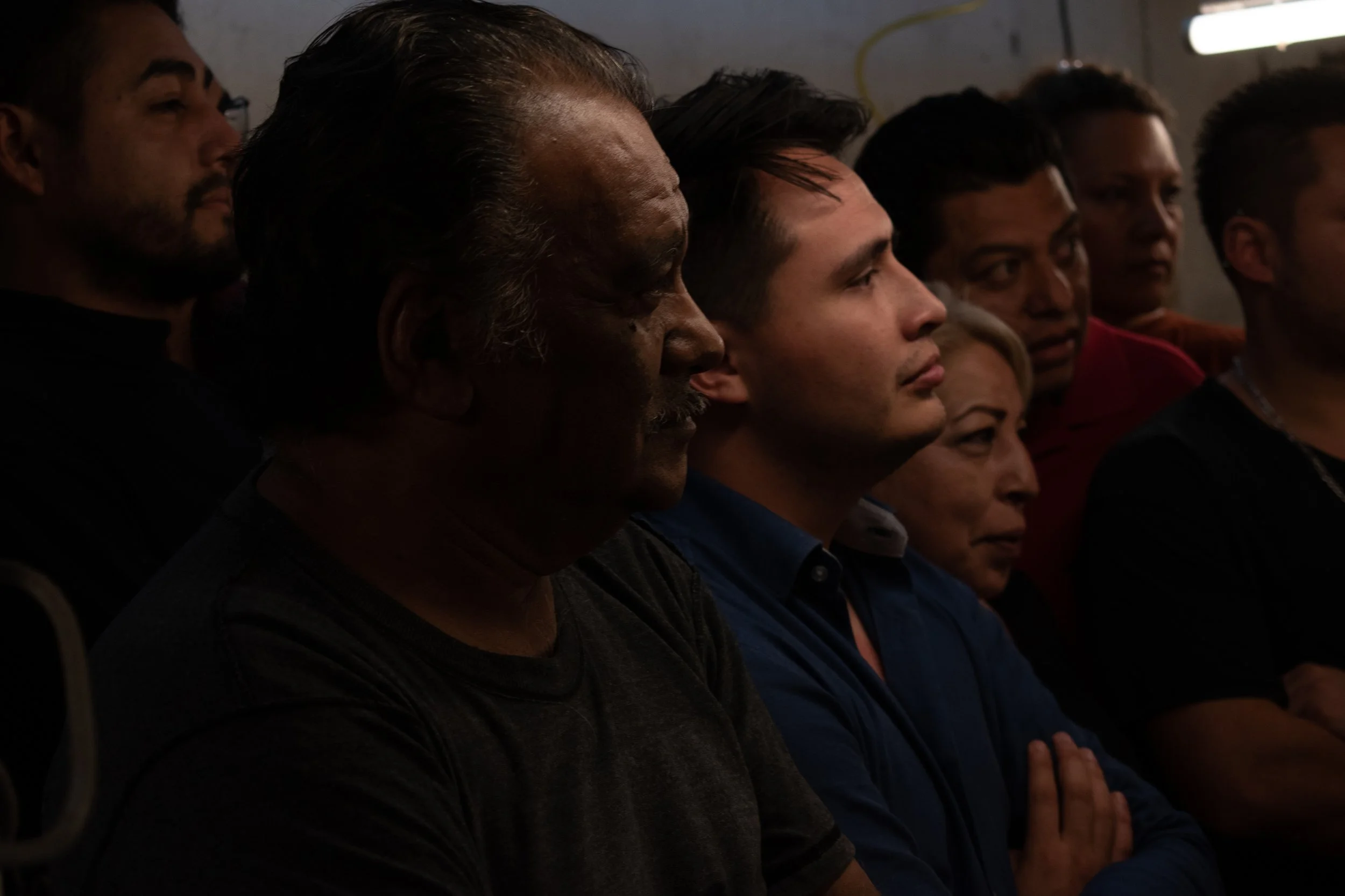 A group of people sitting with their hands folded, possibly attending a presentation or event.