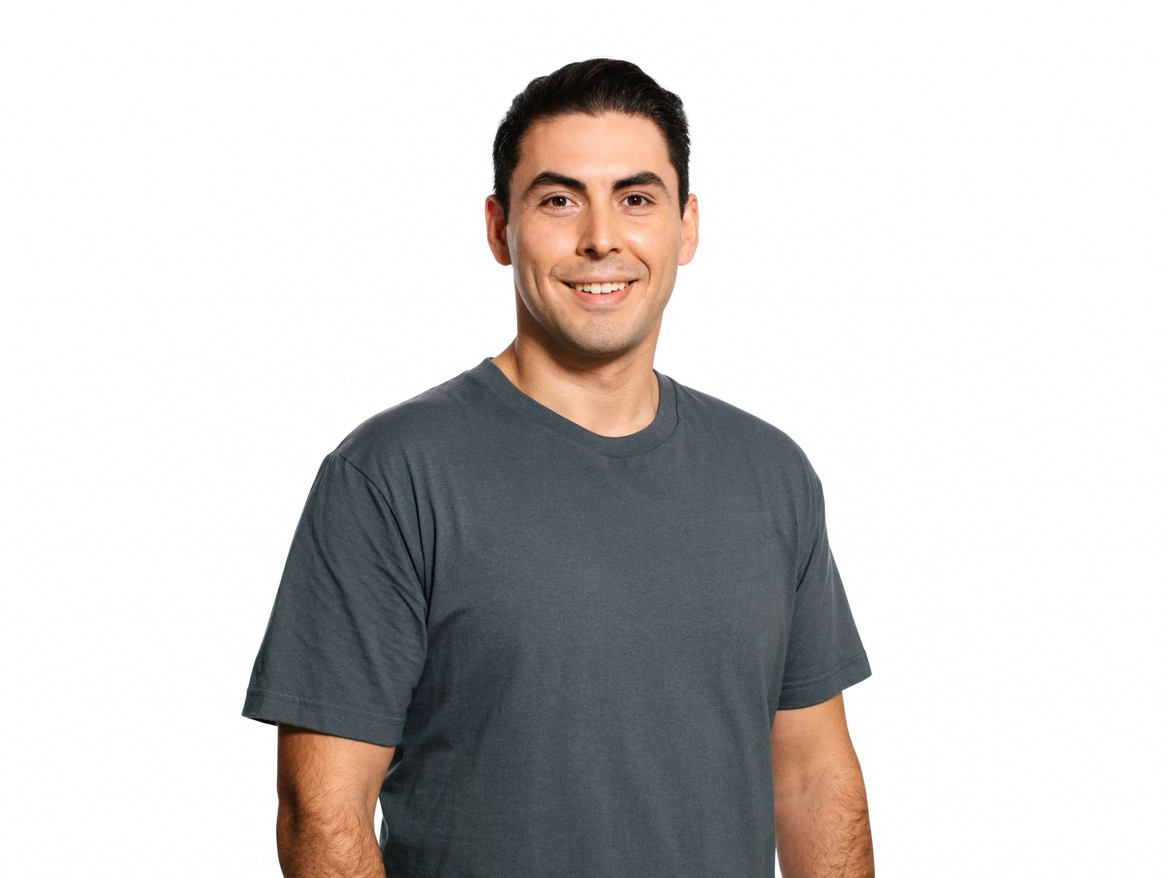 Portrait of a young man with dark hair, smiling, wearing a dark gray t-shirt against a white background.