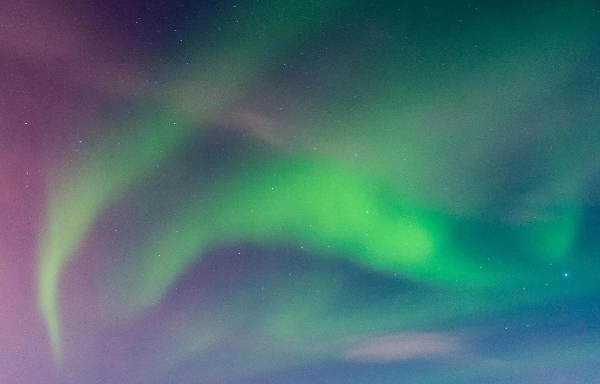 Northern lights lighting up the night sky with green, purple, and blue hues, dotted with stars.