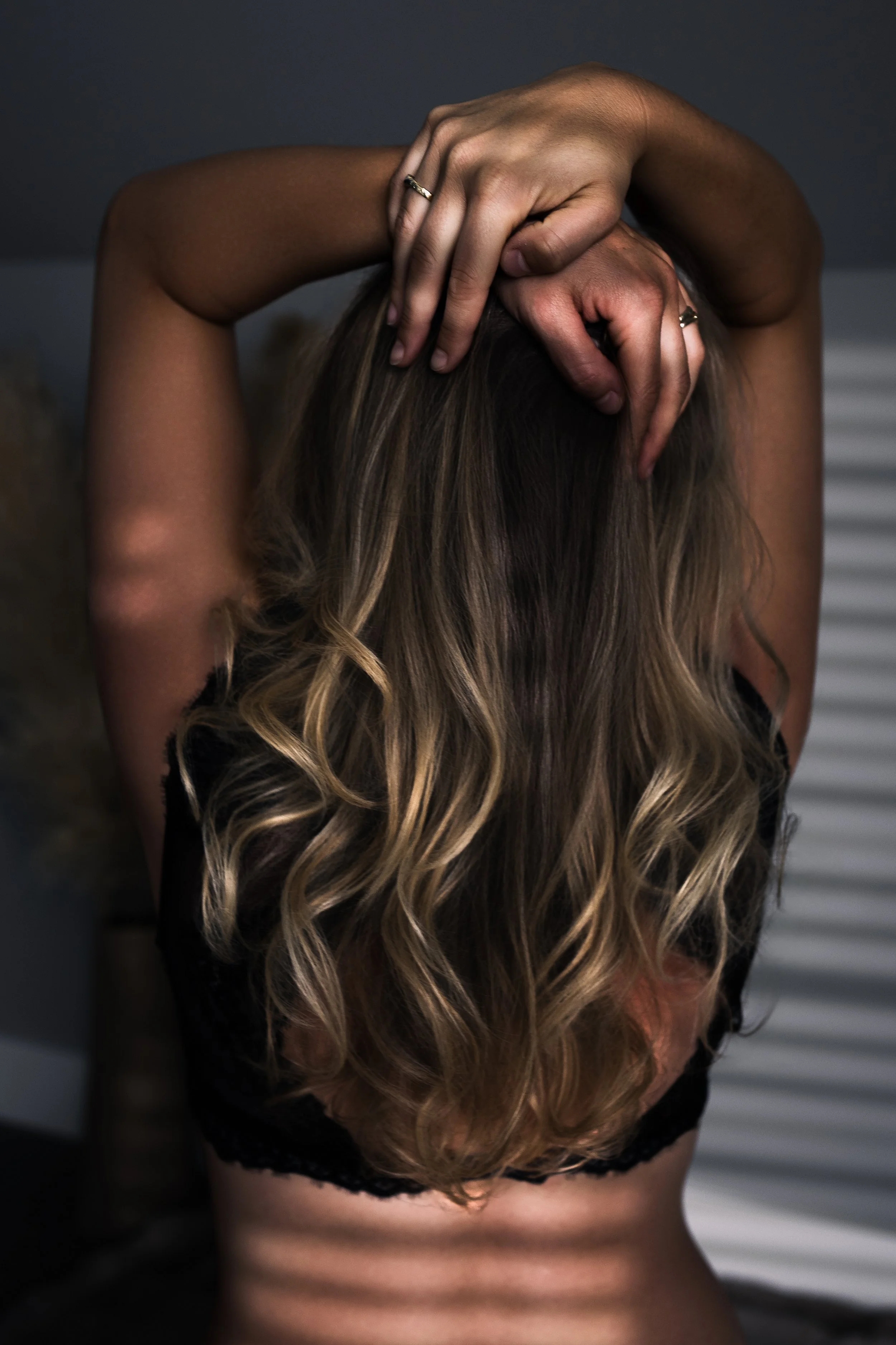 Close-up van een persoon met lang, golvend haar die haar hoofd met beide handen vasthoudt.