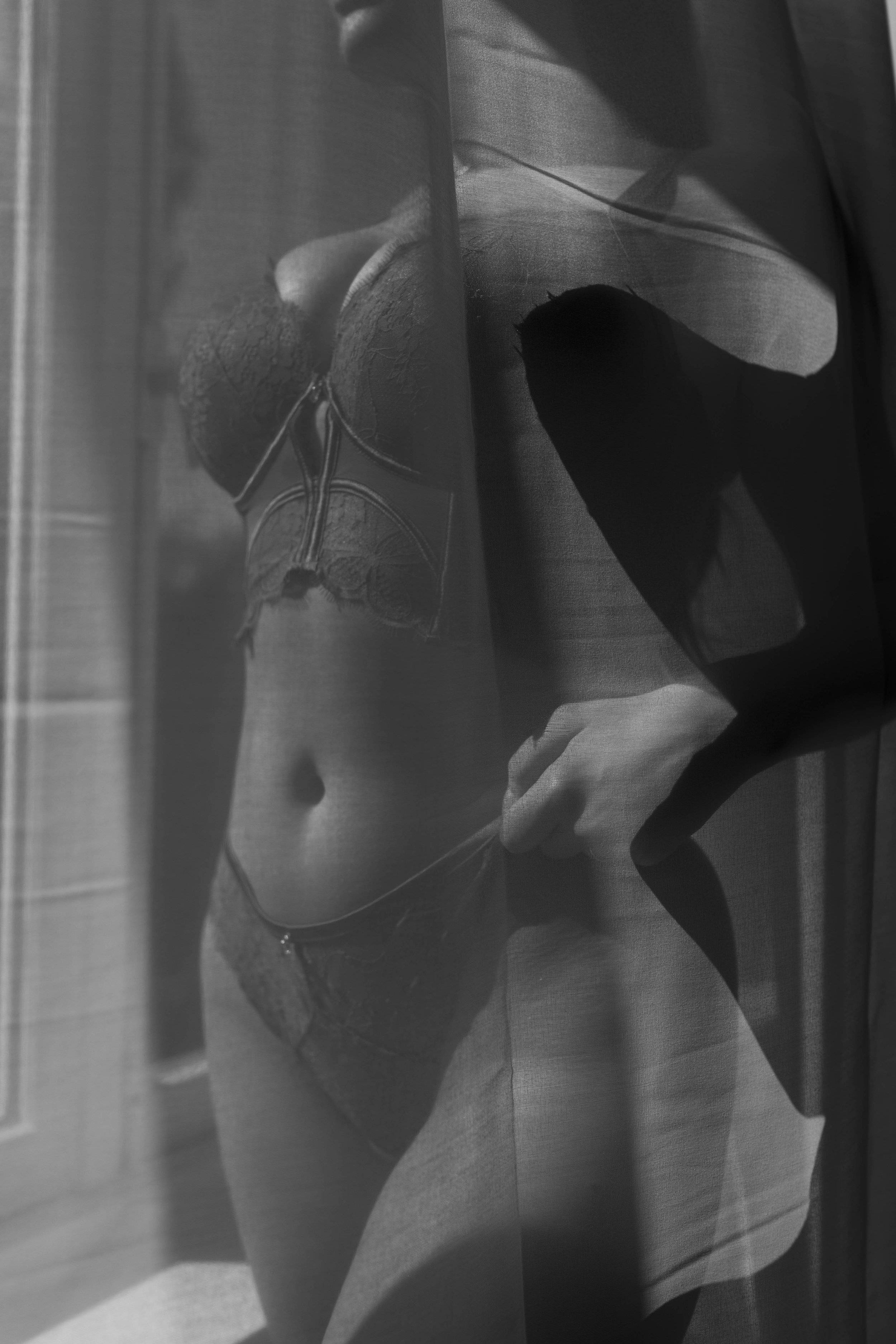 Close-up van een vrouw die lingerie draagt en een rugzak, met nadruk op haar taille en benen, zwart-wit foto.