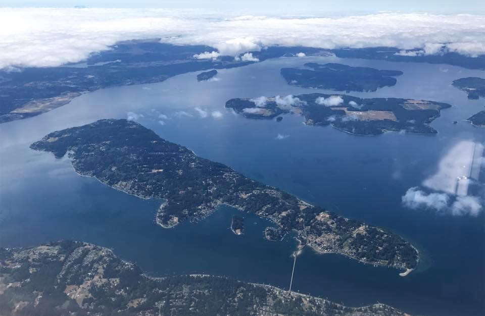 Aerial view of an island with surrounding water, with smaller islands in the distance.