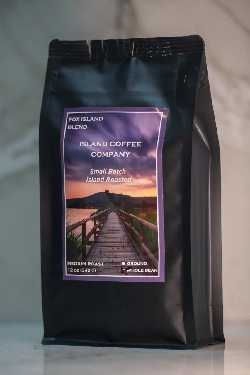 Package of Island Coffee Company Fox Island Blend medium roast whole bean coffee with a scenic label featuring a bridge and island at sunset.
