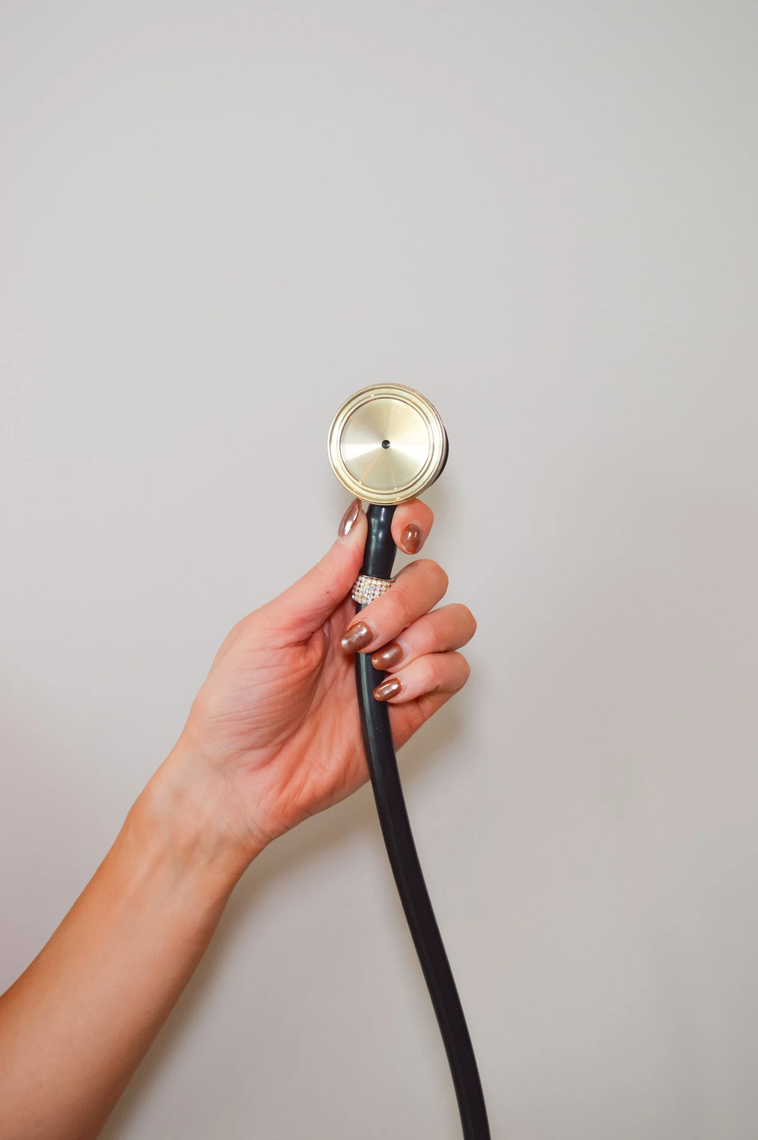 Hand holding a stethoscope against a plain white background.