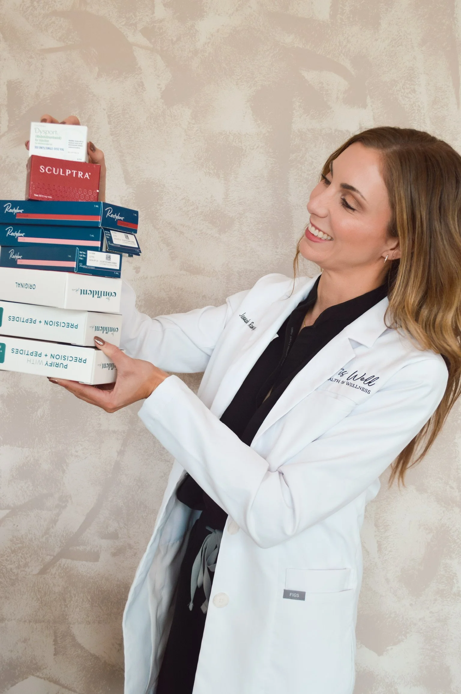 A smiling woman in a white lab coat holding several boxes of products