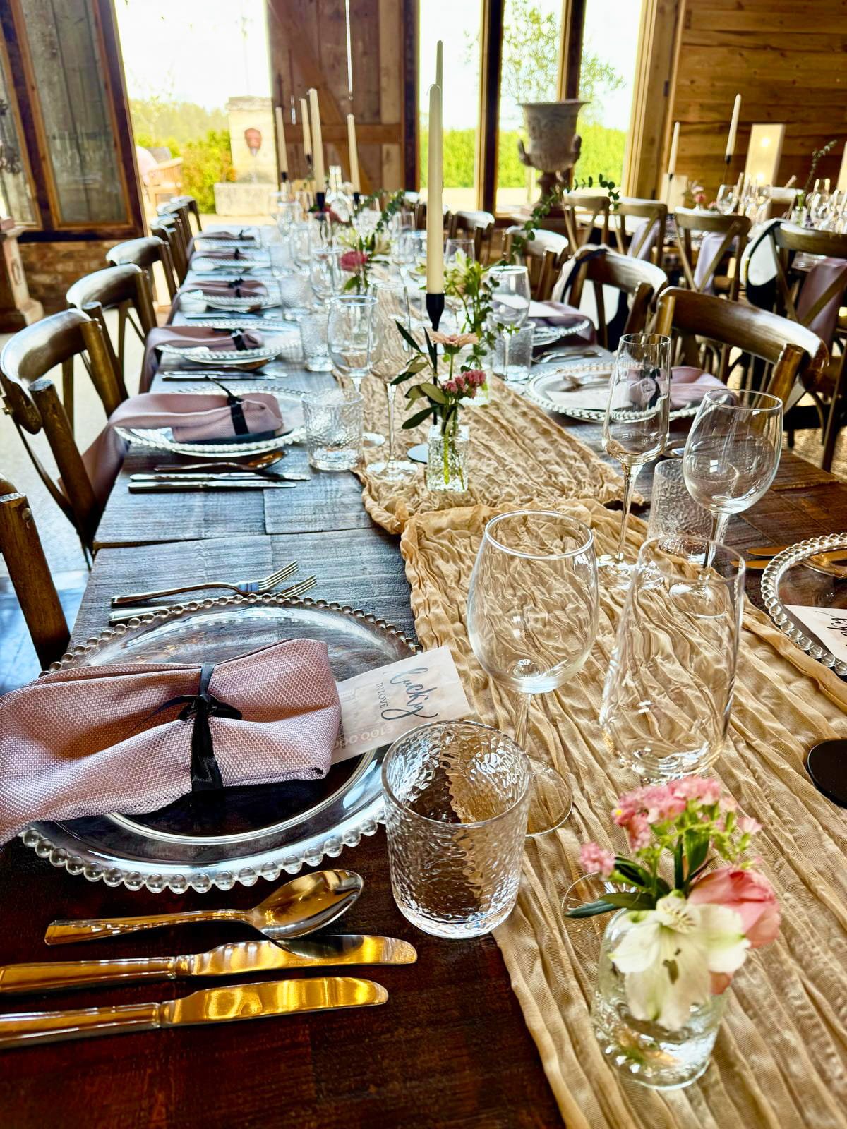 Rustic wedding table setting with runner, glassware, plates and floral centrepieces