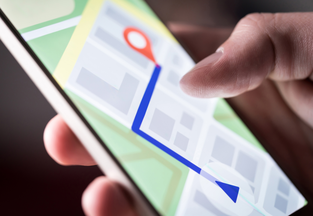 Close-up of a person using a smartphone with a map app showing a route with a red location pin and a declining blue line.
