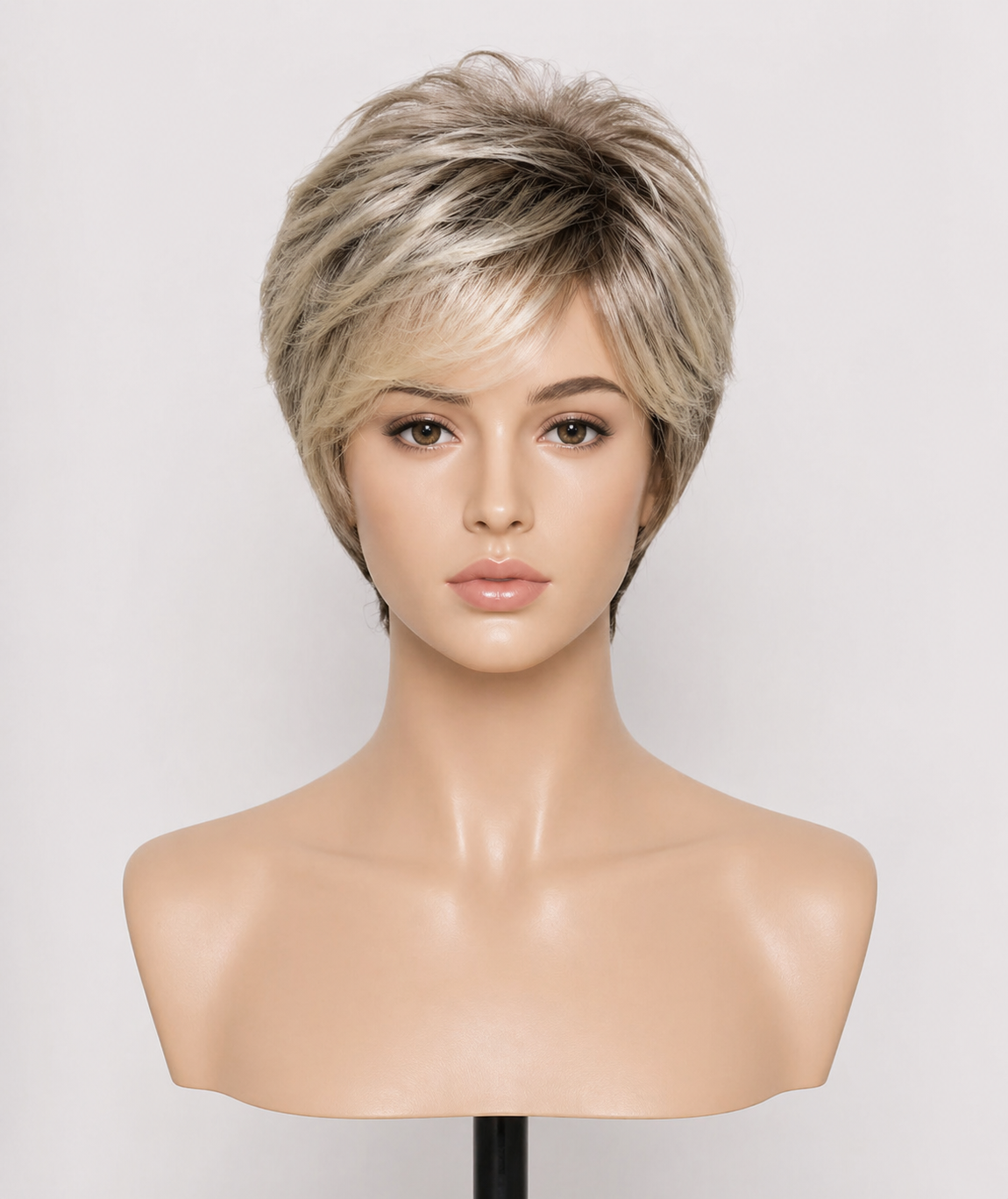 A mannequin head with short medical grade premium raw human hair medical wig, layered, blonde hair styled in a voluminous, textured cut, against a plain light background.