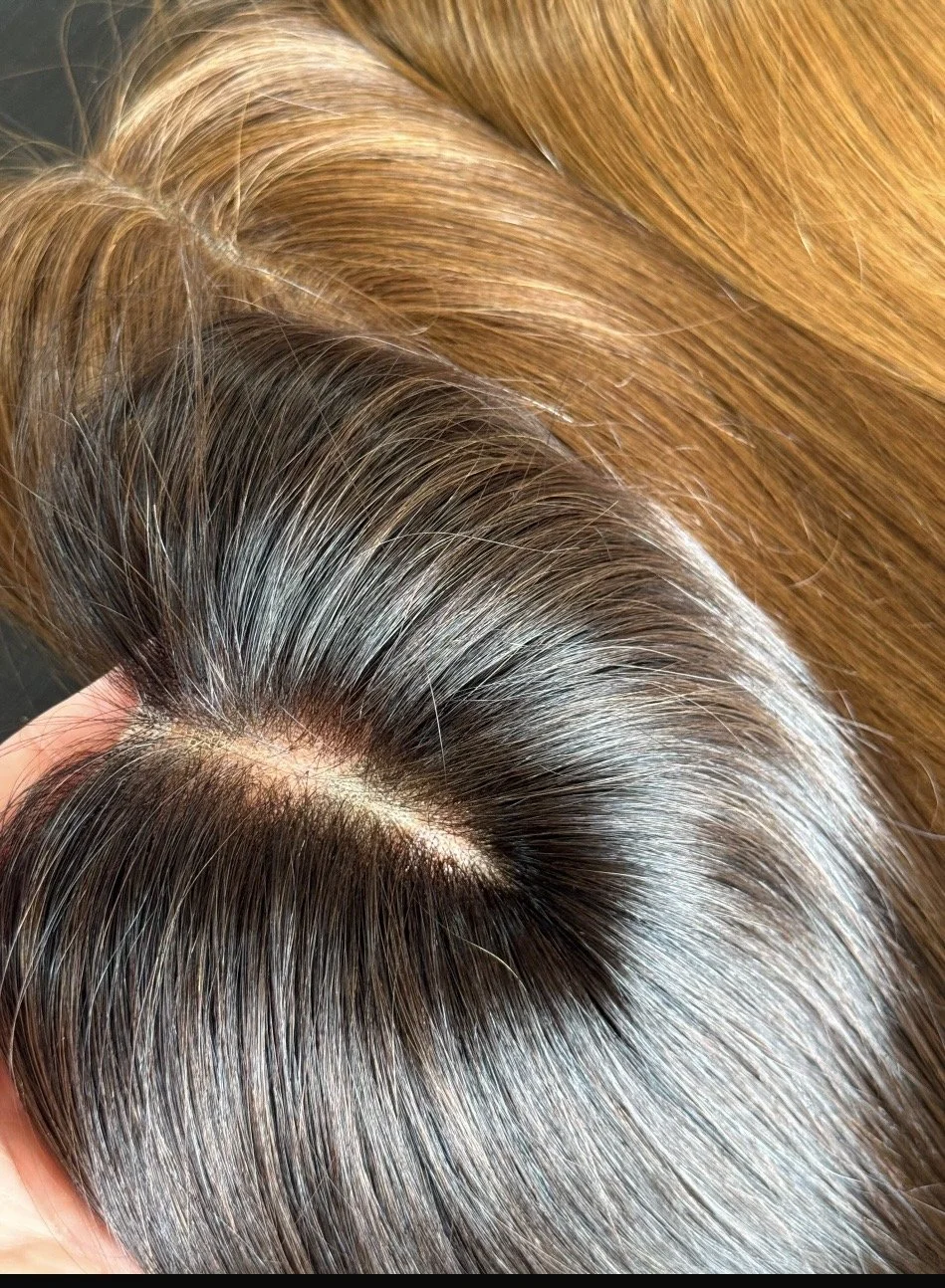 Close-up of a half topper showing hair with realistic scalp, roots and brown hair.