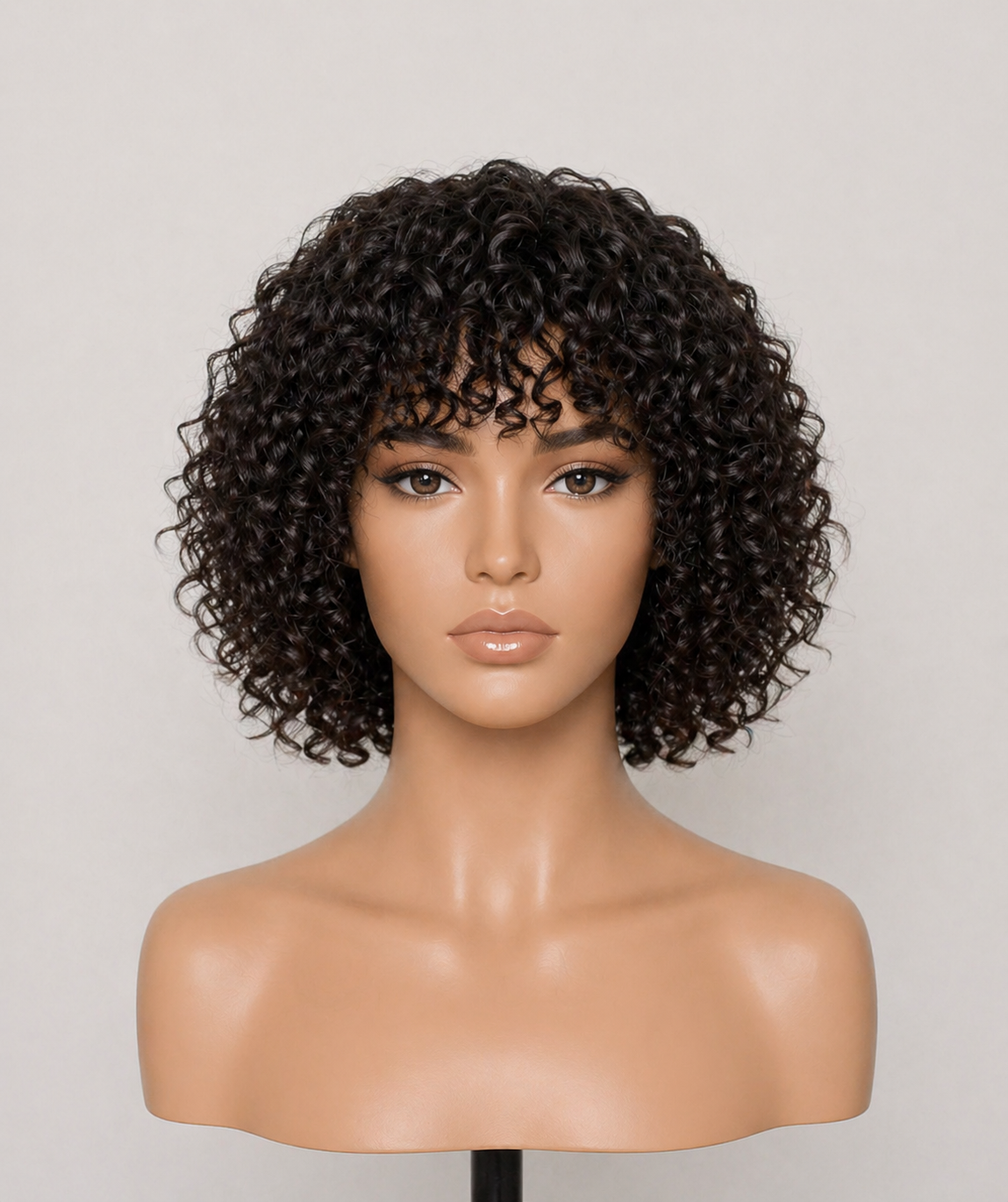 A mannequin head with medical grade premium raw human hair medical wig dark, curly hair, makeup, and bare shoulders, against a neutral background.