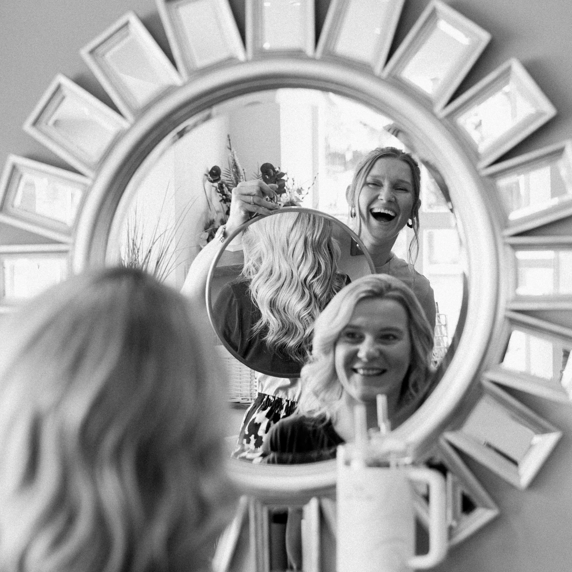 A black and white action shot of Casey styling a client's hair at Hair at Suite 7