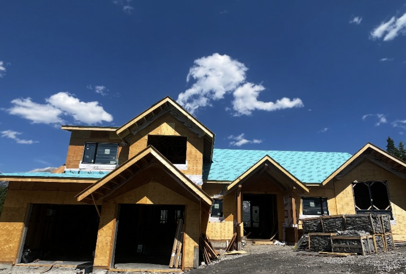 A house under construction with a blue sky and white clouds in the background.