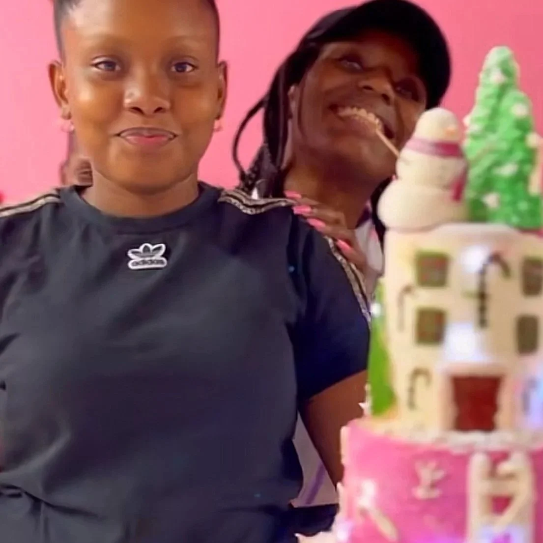 Two smiling women at a birthday celebration, with a decorated birthday cake in the foreground.