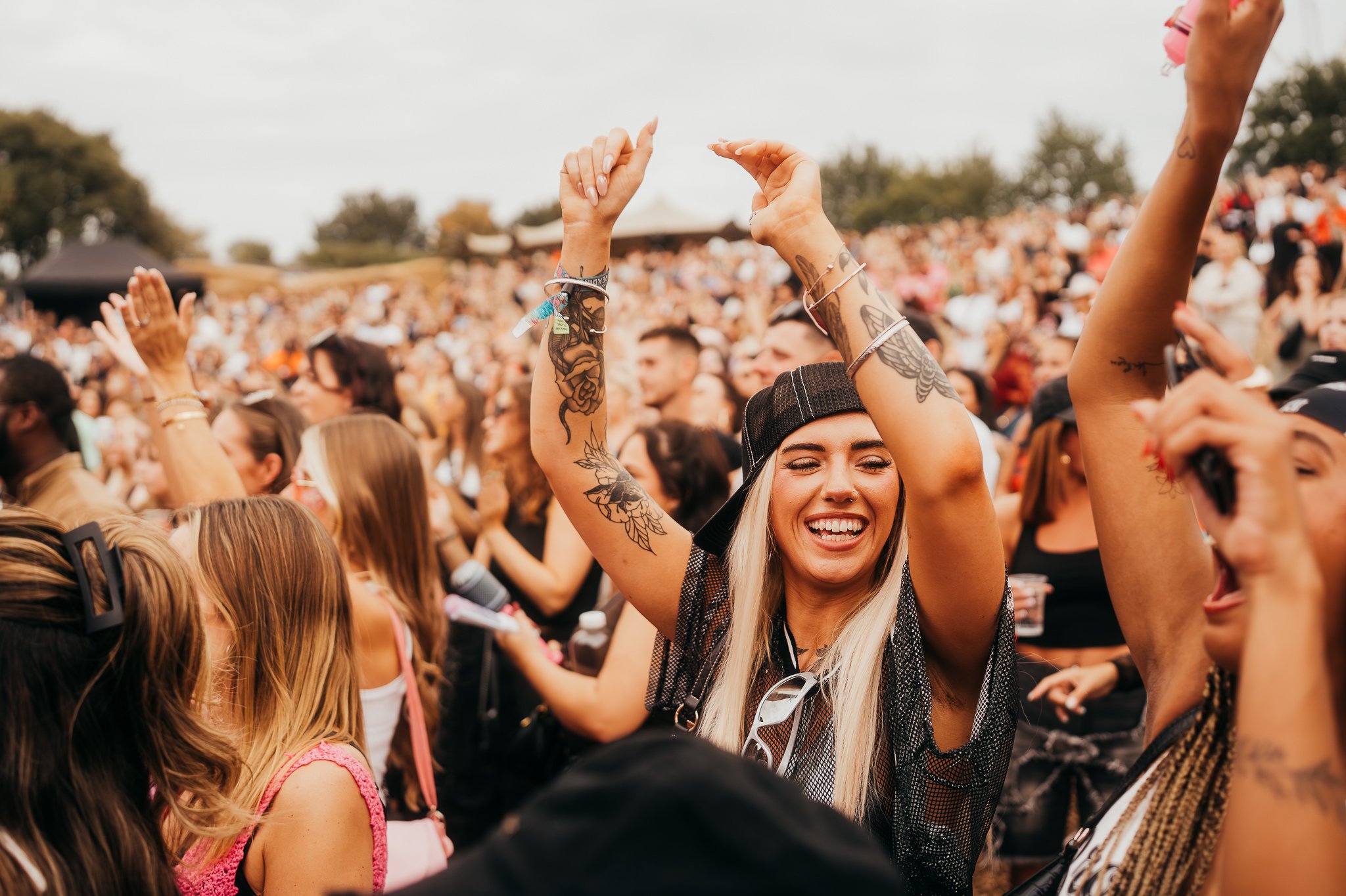 People enjoying a concert outdoors, dancing and smiling.