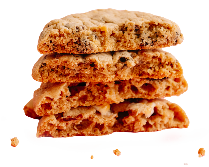 A stack of four chocolate chip cookies against a light pink background.
