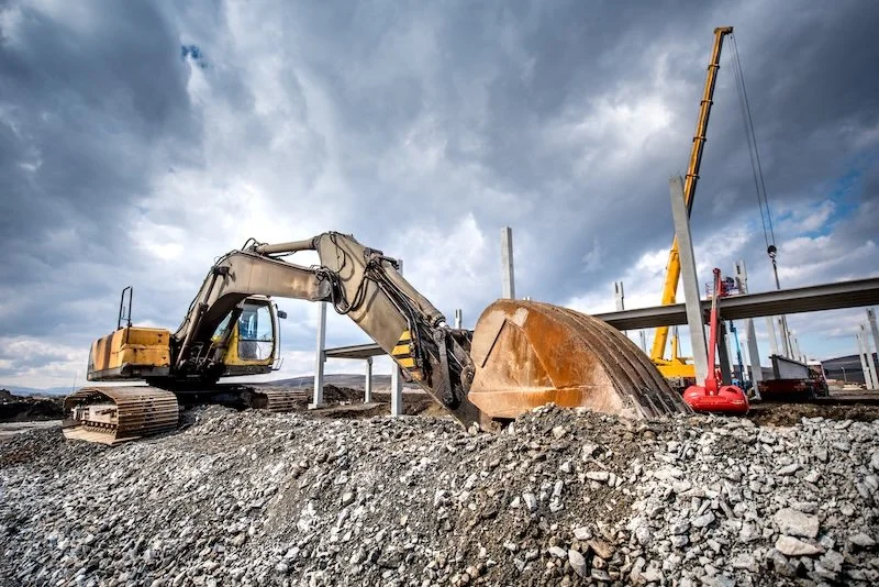 Construction site with an excavator, construction equipment, and a cloudy sky