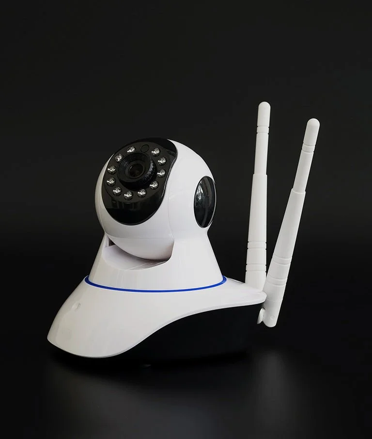 A white security camera with two antennas against a black background.
