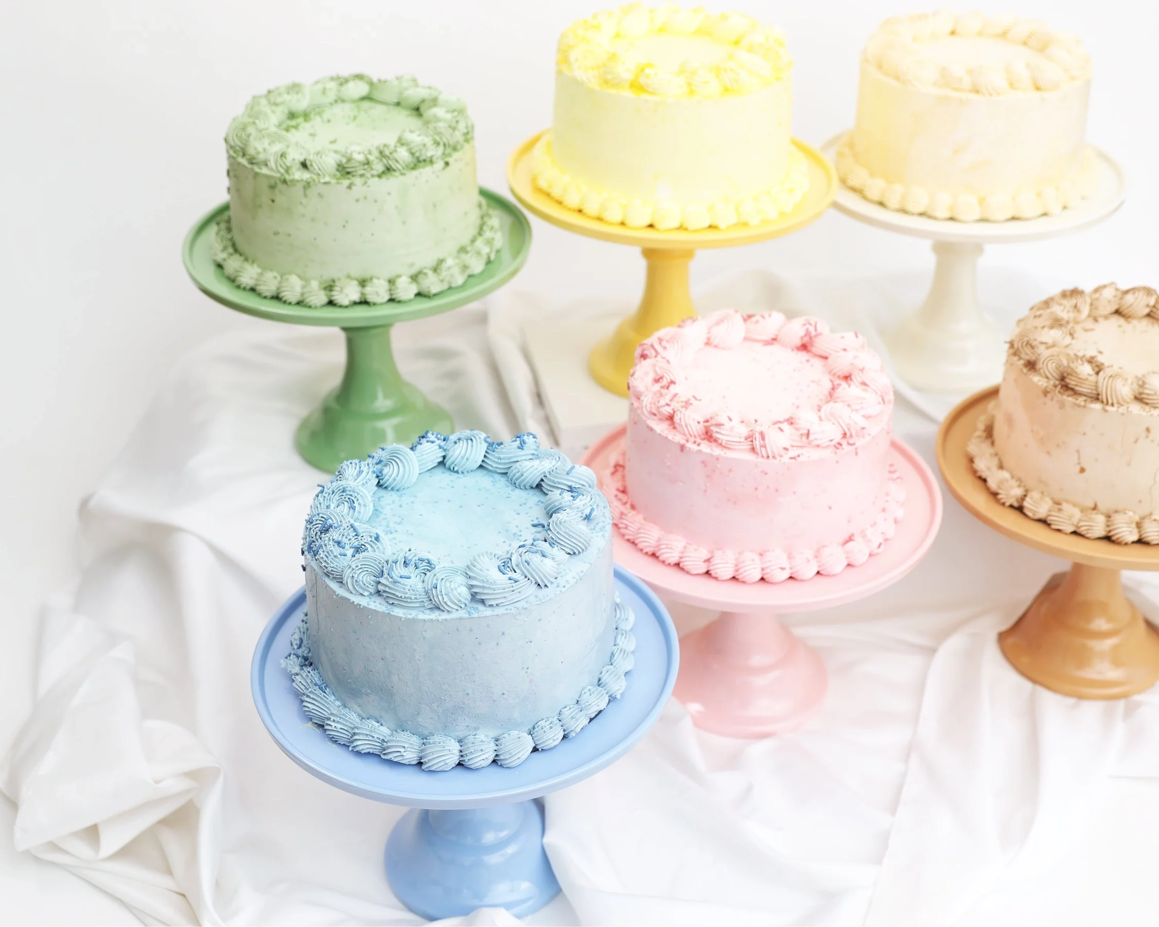 Curated display of colorful birthday cakes on ceramic stands, highlighting the sophisticated aesthetic of our party supplies for Seattle milestone gatherings.