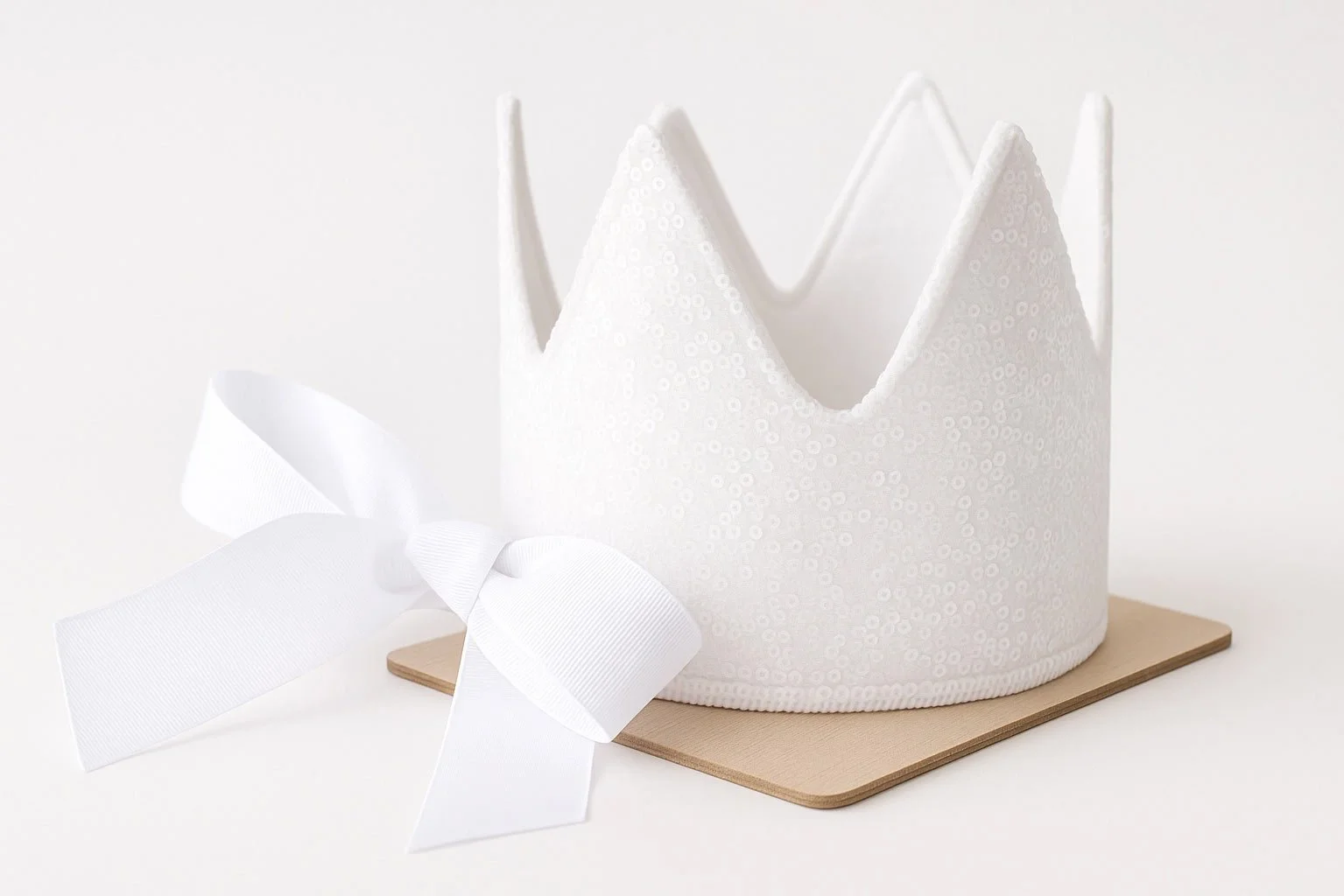 A sophisticated white birthday crown with a white bow accent, a signature piece of our high-end party supplies for Seattle birthday and milestone celebrations.