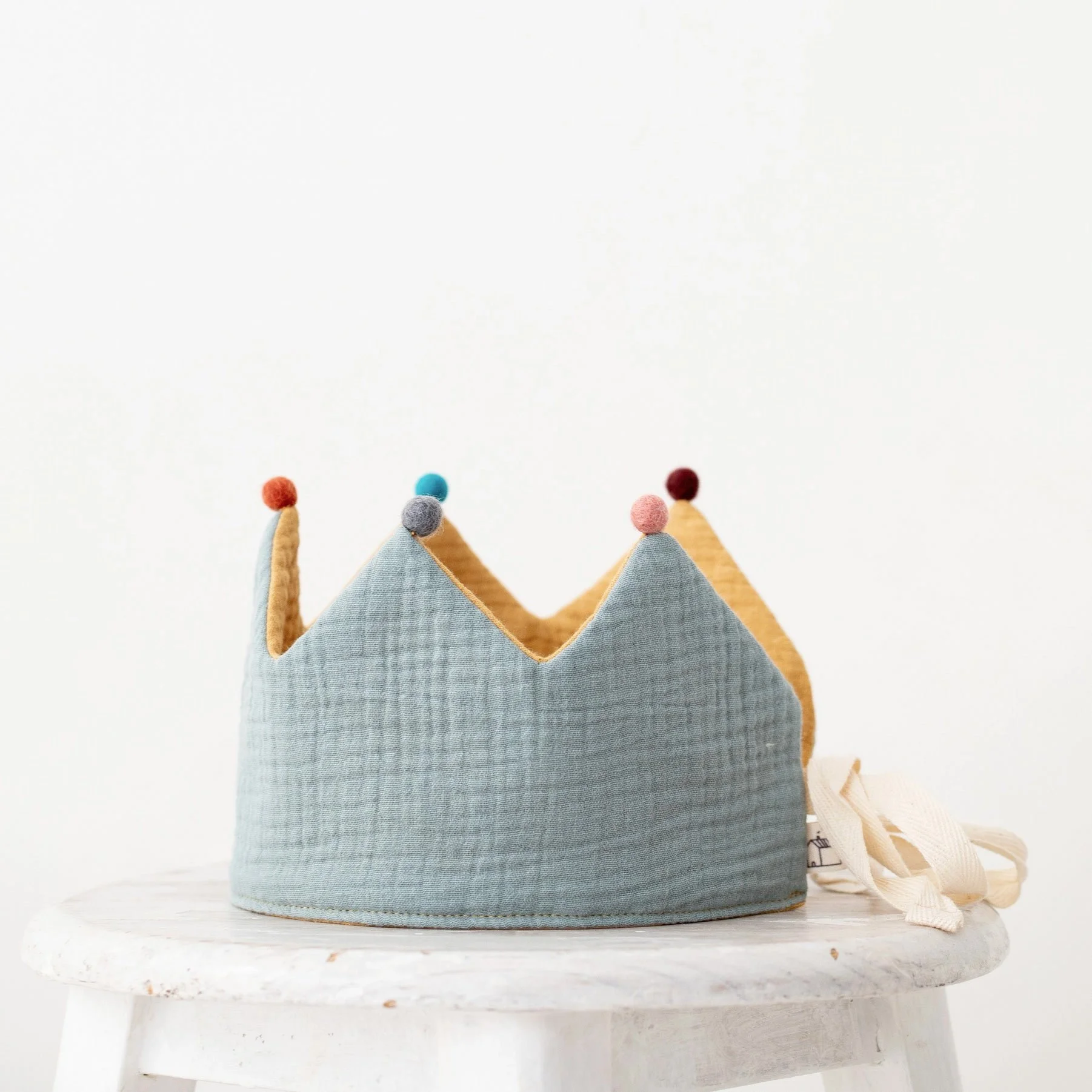 Handcrafted blue linen birthday crown with pom-pom accents, a signature piece of our boutique party supplies serving families in Madrona and Madison Park.