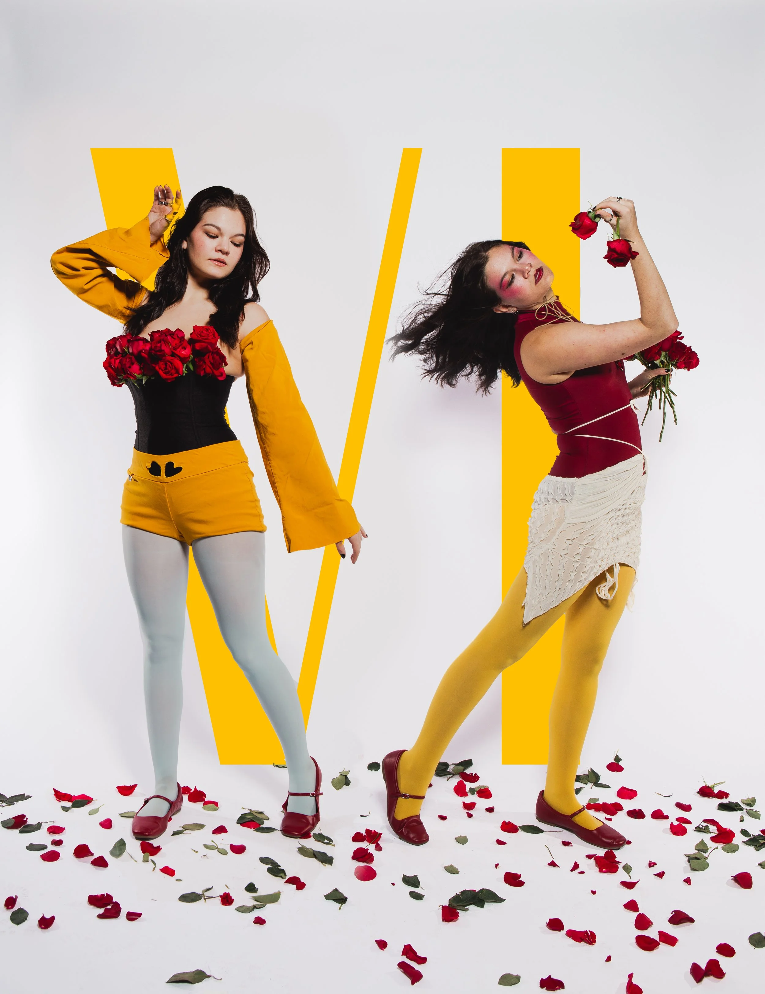Two young women in colorful outfits standing on a white background with scattered rose petals and yellow geometric shapes. One woman wears a yellow jacket and shorts, the other a red sleeveless top and skirt, holding roses.