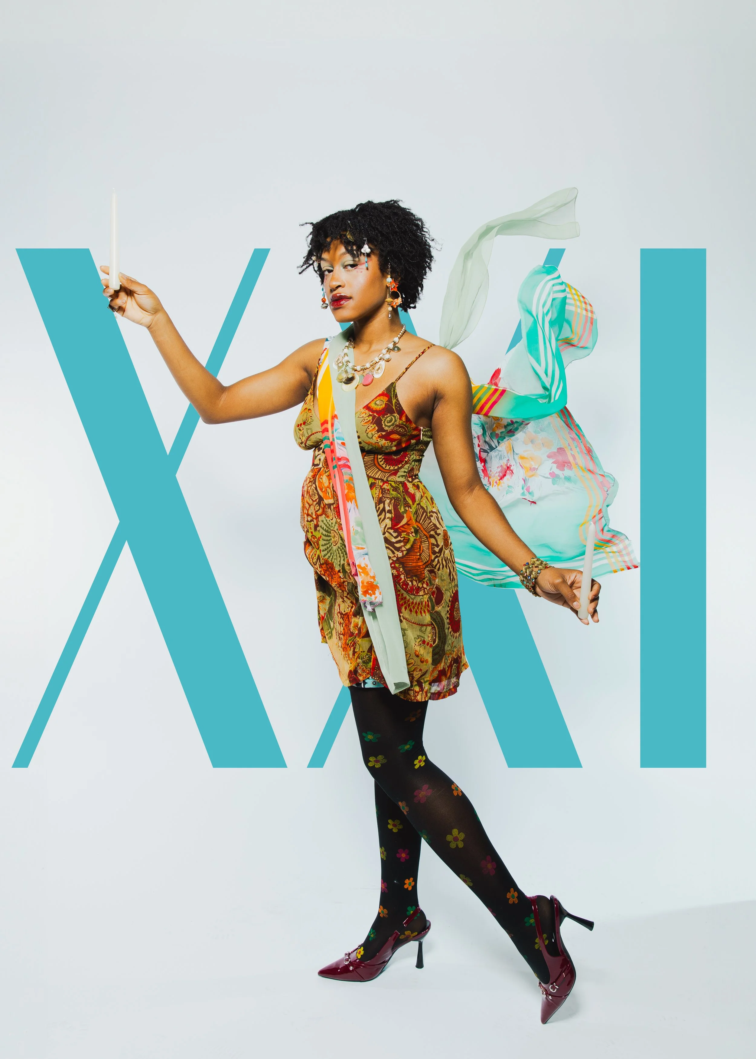 A woman wearing a colorful, patterned dress with layered jewelry, black tights with multicolored flower patterns, and red high heels stands in front of a white background with the word 'VIVA' across the image.