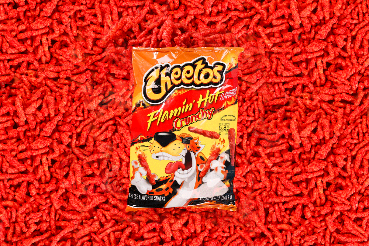A bag of Flamin' Hot Cheetos Crunchy snack on a bed of red snack puffs.