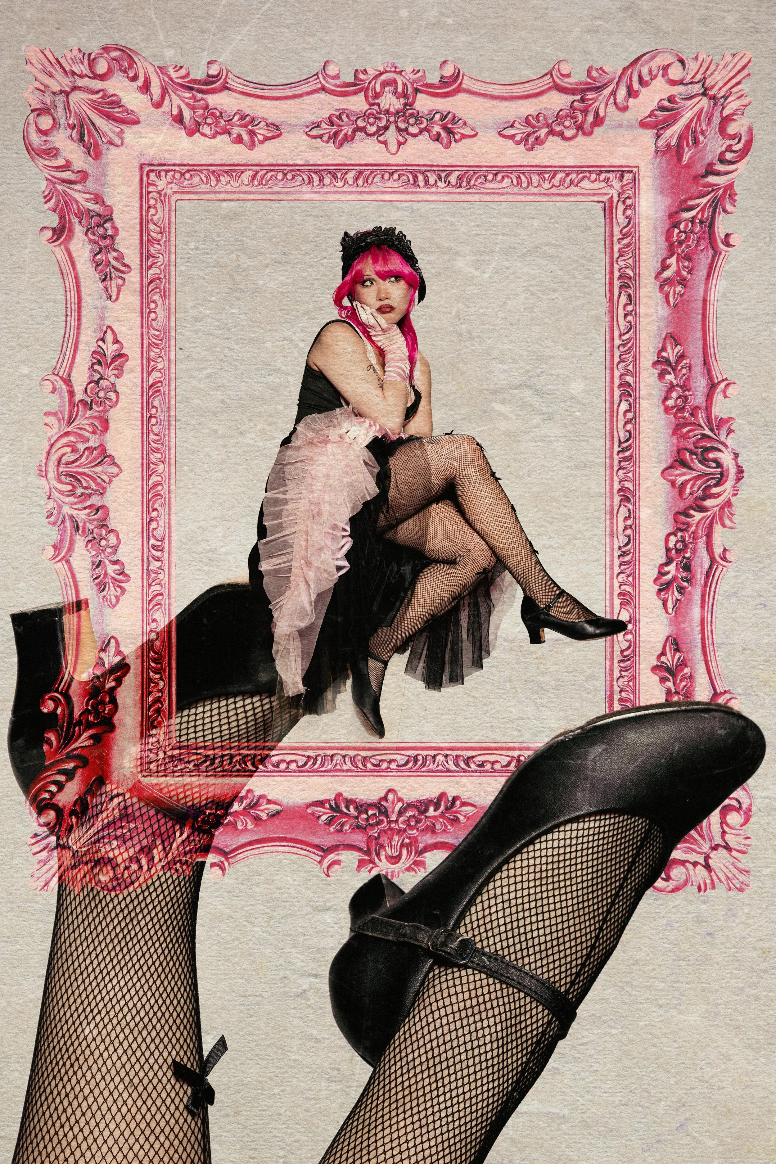 A woman with pink hair, wearing fishnet stockings, a black dress, and black heels, sitting on the floor inside a large, ornate, pink picture frame against a plain wall.