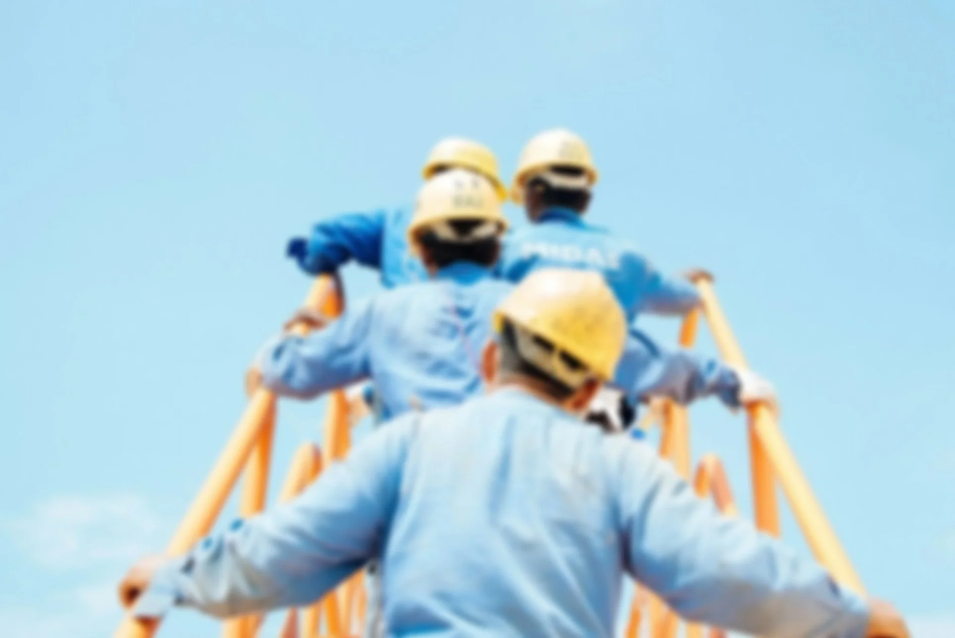 Construction workers with yellow hard hats ascend a yellow ladder against a blue sky.