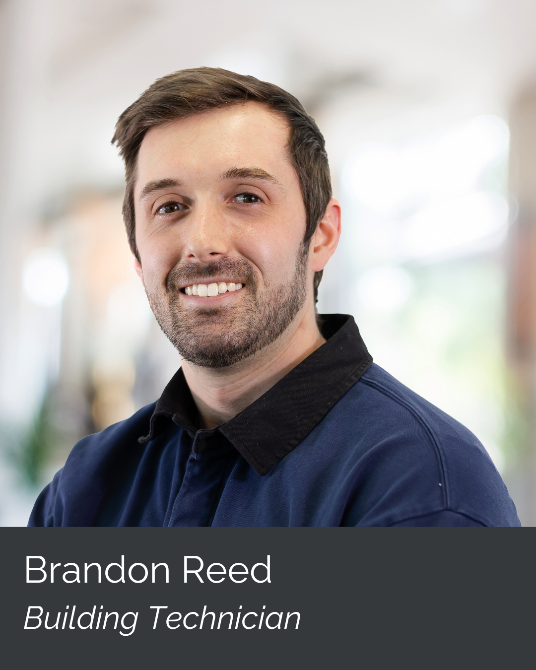 Portrait of Brandon Reed, building technician, smiling in an indoor setting with a blurred background.