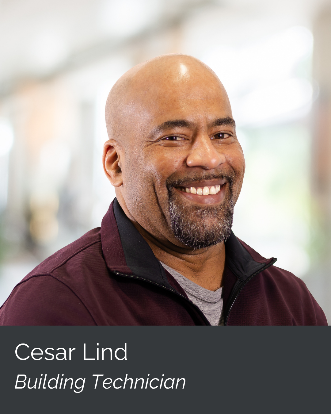 Portrait of Cesar Lind, a smiling building technician, in a professional setting with blurred background.