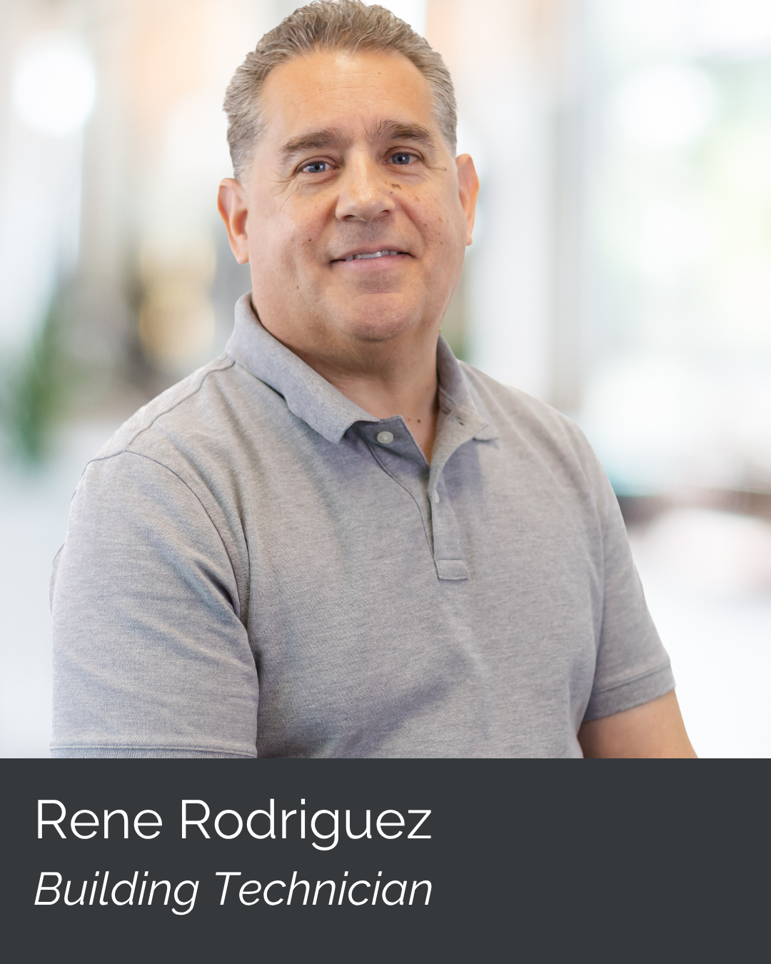 Portrait of Rene Rodriguez, a building technician, wearing a grey polo shirt in an indoor setting with blurred background.