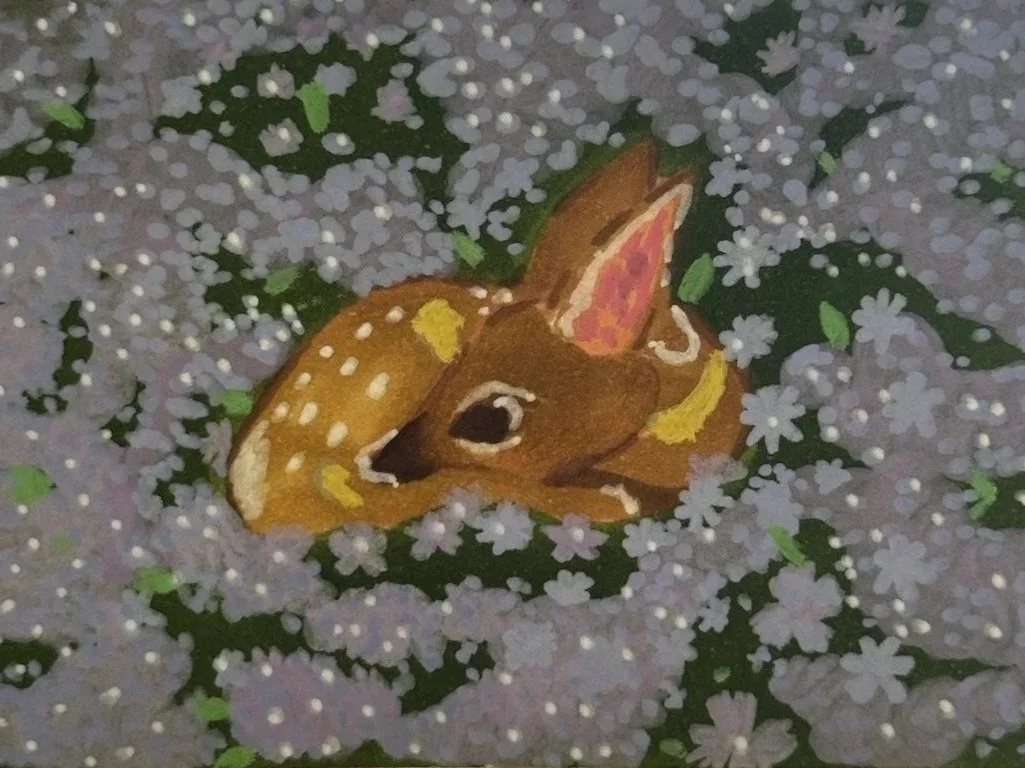A small photo of a painted deer face among group of tiny white and purple flowers.