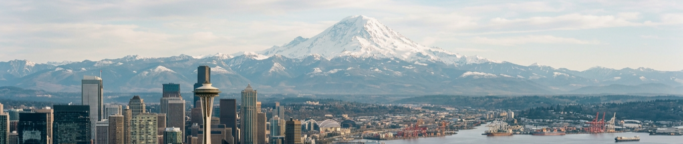 A city skyline with the Space Needle in the foreground and snow-capped mountains in the background, including Mount Rainier.