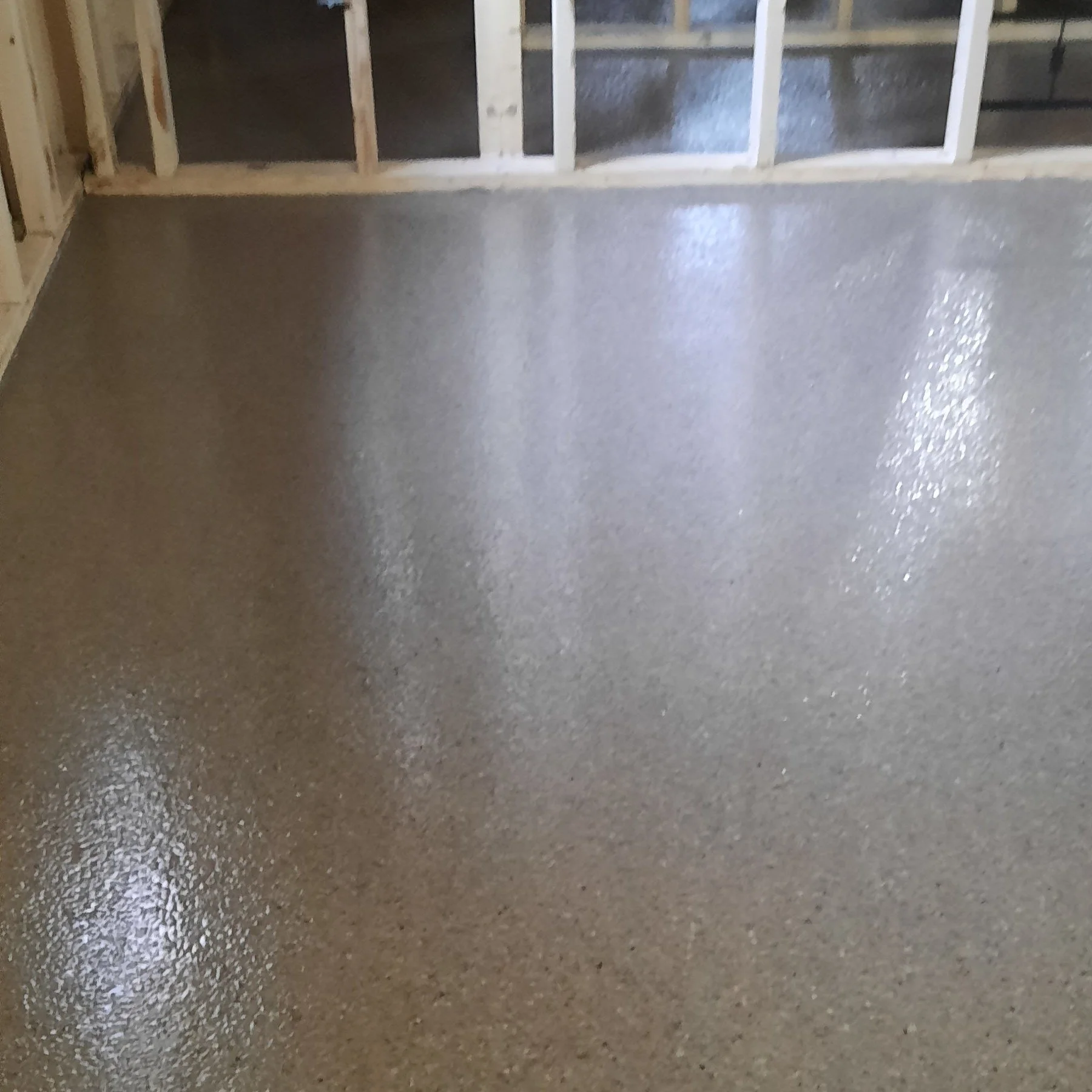Freshly poured concrete floor in an unfinished room with exposed wooden framing.