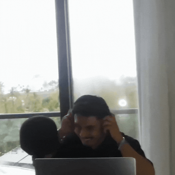 Aaron Tapia con audífonos en una habitación de hotel, frente a una ventana, produciendo una canción.