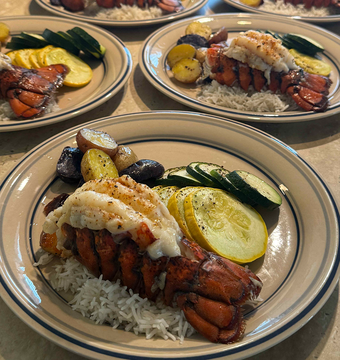 Broiled Lobster Tails served with Coconut Rice, Roasted Fingerling Potatoes, and Zucchini & Squash 