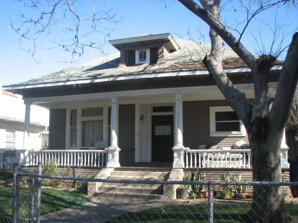 This handsome and virtually intact Colonial Revival house at 213 N Avenue 55 is highlighted by a full width front porch with four Tuscan columns and colonial balustrades on the porch railing. The front door is located in a central alcove with a trans