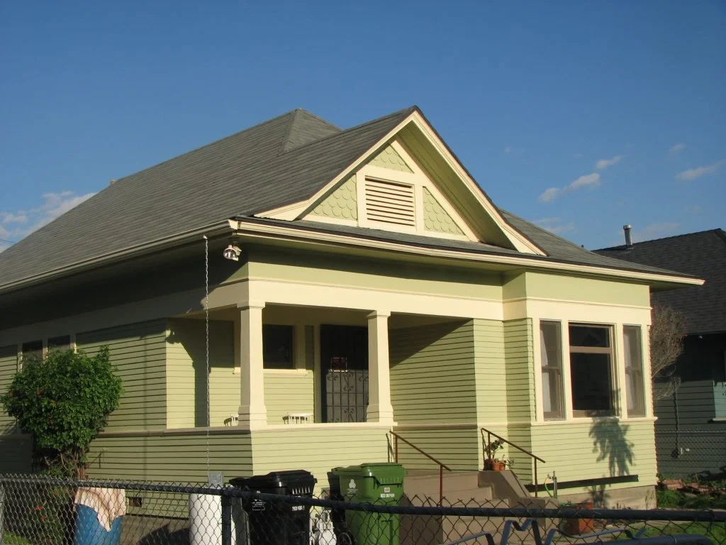 This charming bungalow, known as Takano House, features a dormer with fish scale shingles situated above the porch and a square bay on the right side of the house. Because of the pyramidal roofline and its massing, this structure can be described as 