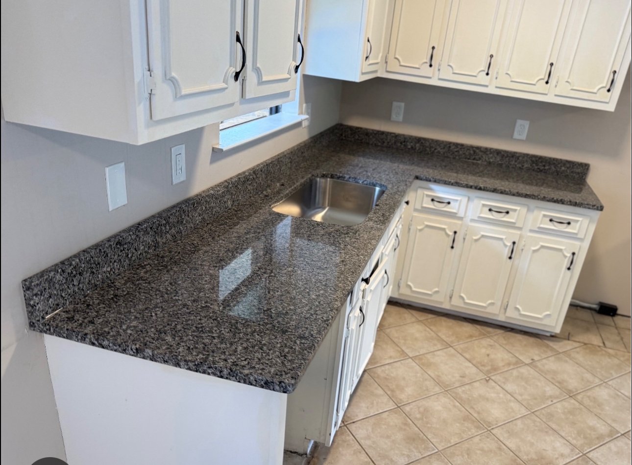 Kitchen with white cabinets, granite countertops, and a stainless steel sink