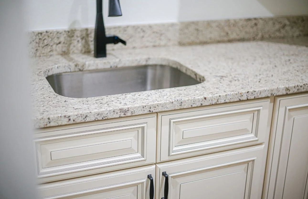 Kitchen sink with granite countertop and beige cabinets
