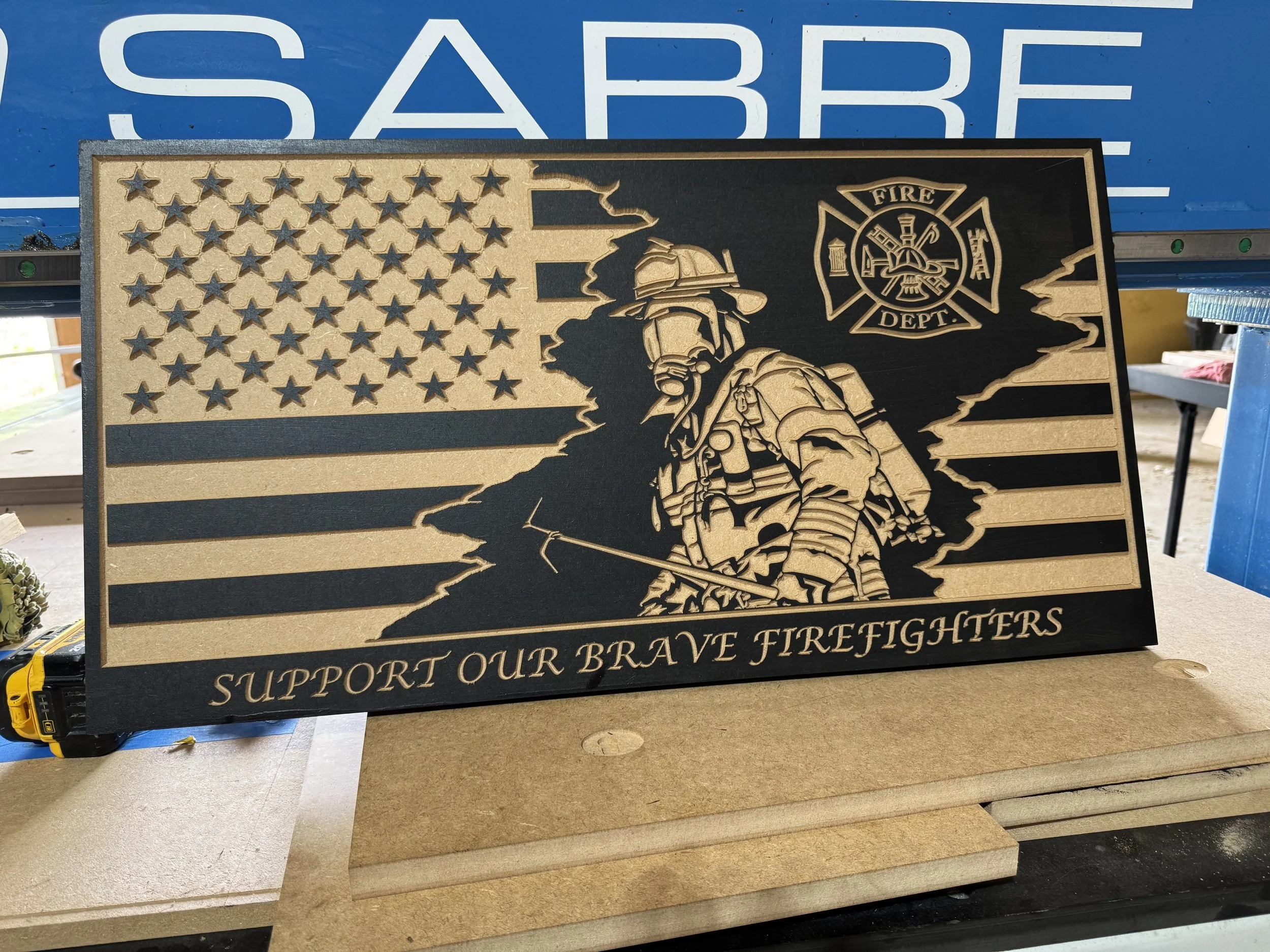 A wooden plaque featuring a firefighter support design with an American flag and a firefighter illustration, with the text "Support Our Brave Firefighters".