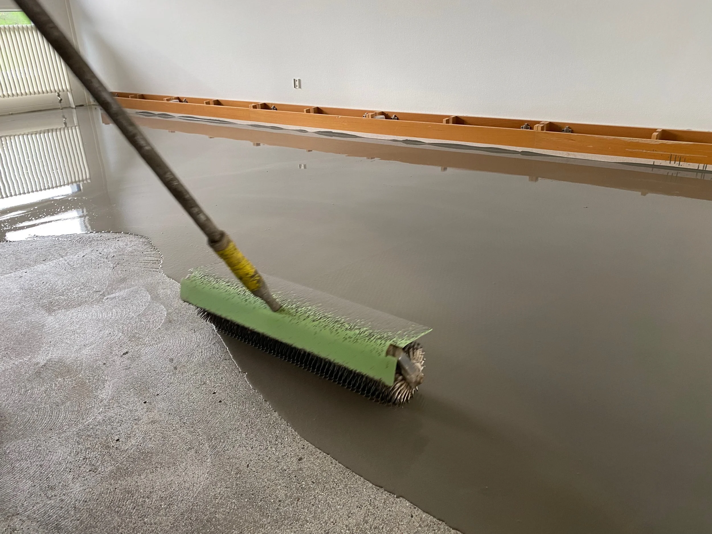 Boden wird geglättet mit einer großen Glättkelle in einem Raum.
