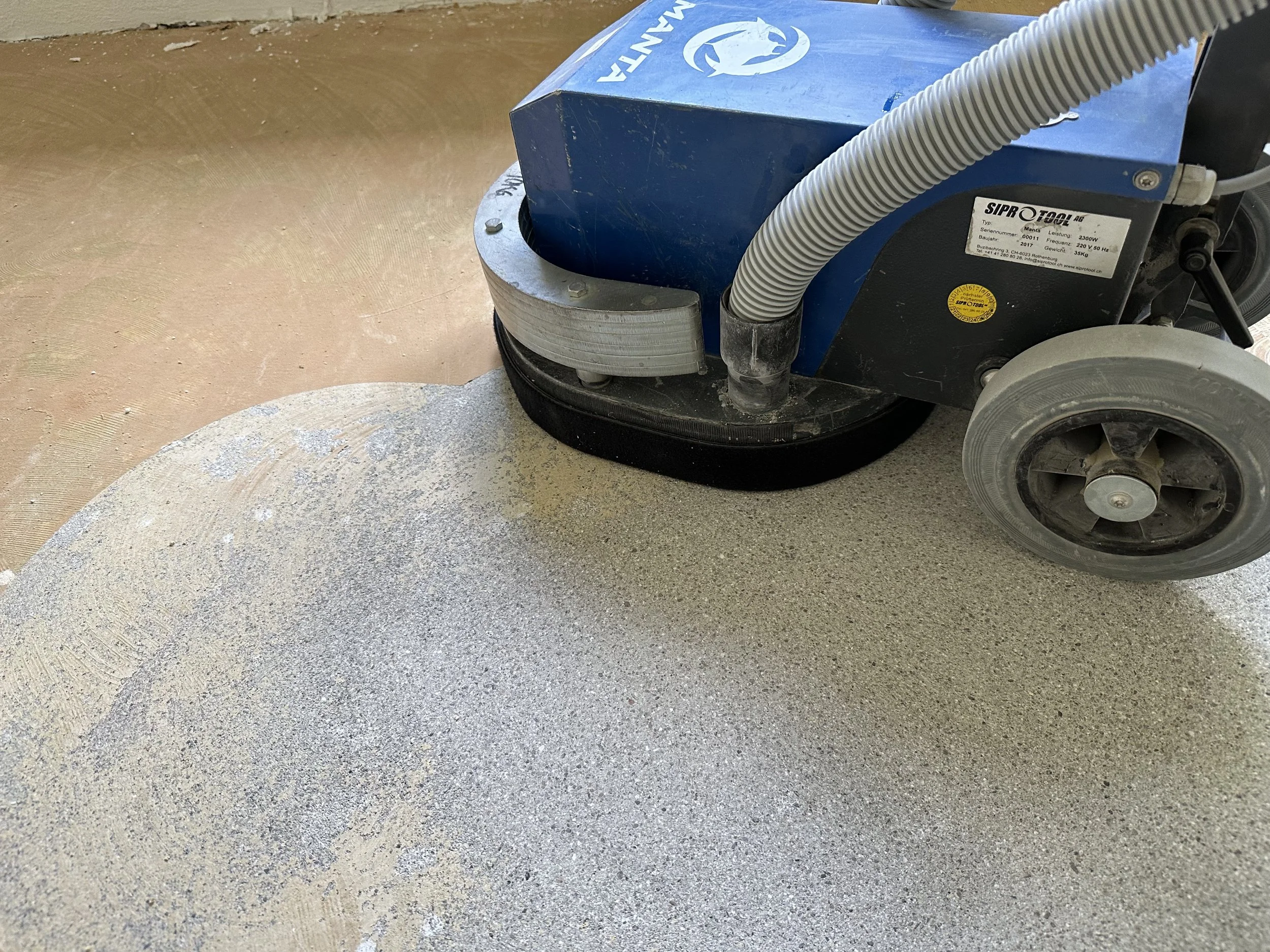 Bodenreinigungsmaschine, die Staub und Staubpartikel auf einem Boden mit einem runden Polierpad entfernt.