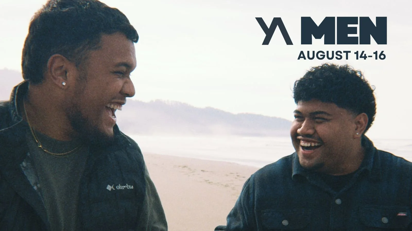Two men laughing and talking on a beach during the daytime.